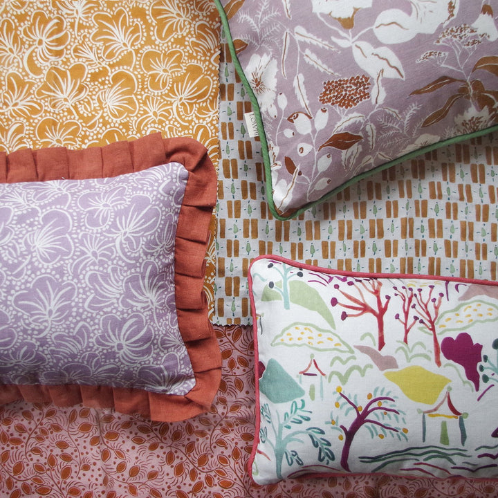 lowri-night-garden-lilac-rust-terrocotta-green-piped-linen-cushion-british-textile-designer-flat-lay-fabrics