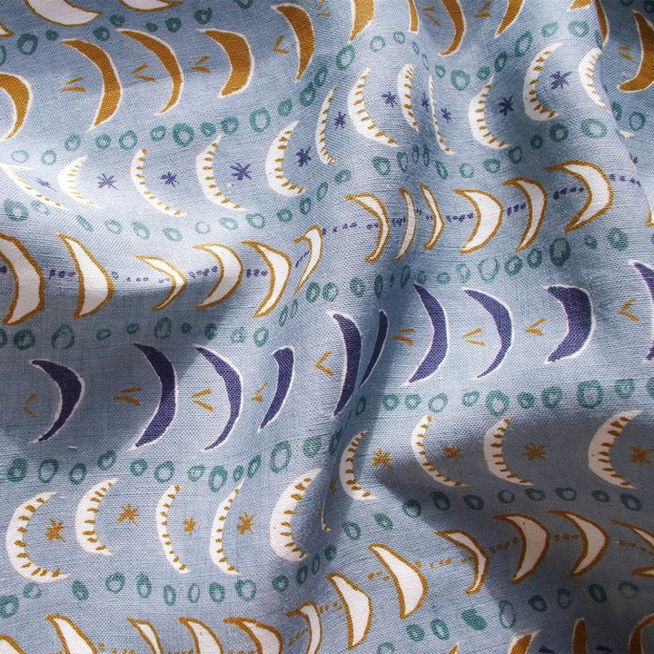 Lowri-textiles-mini-moons-linen-blue-crescent-moon-print-repeat-starts-ditsy-blue-navy-white-ochre-green-sweet-pattern-kids-childrens-textiles-fabric-british-printed